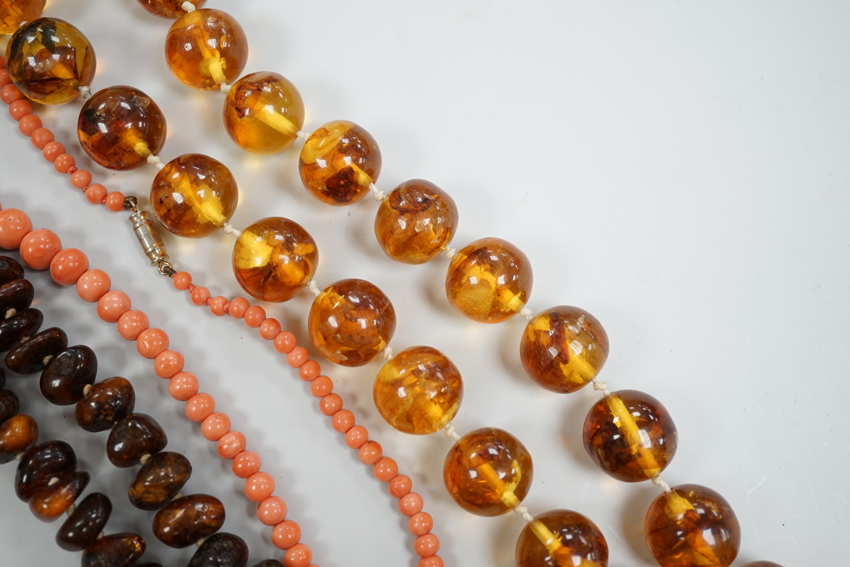 A coral bead necklace, 44cm and two amber bead necklaces.